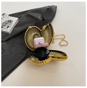 Detailansicht der goldenen Muschel-Clutch mit Metallkette auf elegantem Hintergrund