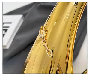 Makroaufnahme glänzender goldener Metallbeschläge und ovaler Ketten an der Acryltasche
