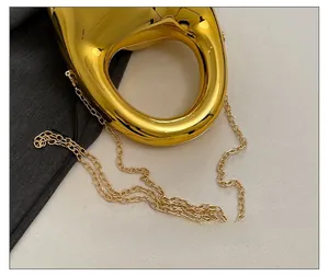 Detail shot of the exquisite golden metal chain strap on a metallic acrylic handbag