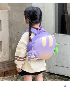 Side view of a purple gradient carrot-shaped backpack on a girl with matching coin purse