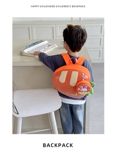 Kid wearing carrot shaped orange backpack with a round coin purse and adjustable straps