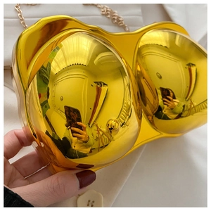 Close-up of heart-shaped gold mirror clutch bag with elegant metal chain strap