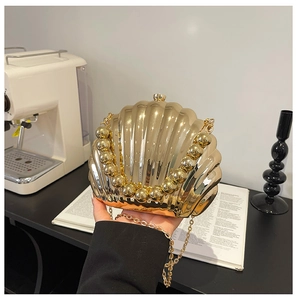 Golden seashell clutch bag with pearl handle and chain strap in luxury interior setting