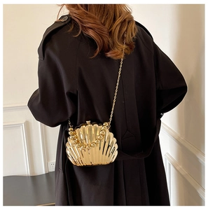 Close-up of golden scallop evening bag featuring beaded handle and metallic chain strap