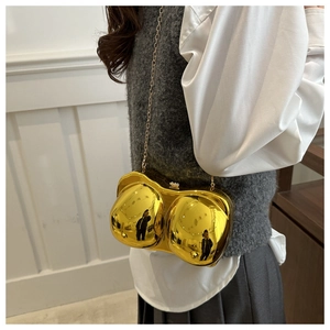 Macro detail of a gold mirrored acrylic clutch in creative female bust shape with metal chain