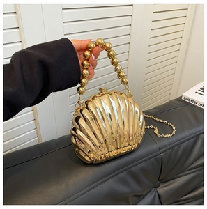 Detailed macro view of scallop shell evening bag with golden metallic texture and bead handle