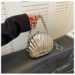 Macro view of silver shell evening bag with textured metallic surface and beaded handle