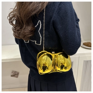 Detail of gold mirror acrylic bra-shaped bag with metal chain strap and top clasp