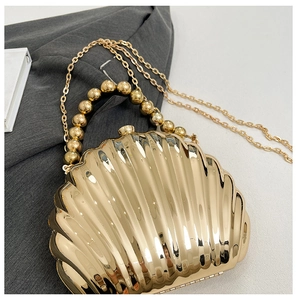 Detail of a golden scallop shell evening bag with beaded handle and chain strap