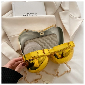Detail of golden heart-shaped hard shell evening bag with chain strap and silver lining
