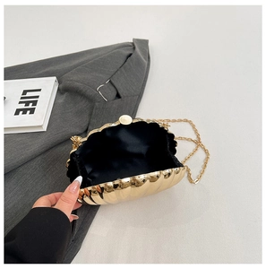 Detail of golden shell evening bag with metallic finish and delicate chain strap