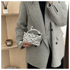 Detail der silbernen Acryl-Clutch mit Eisriss-Textur und Metallgriff in Gepard-Optik