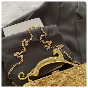 Nahaufnahme der goldenen Abendtasche mit Leoparden-Griff und Hammerschlag-Textur