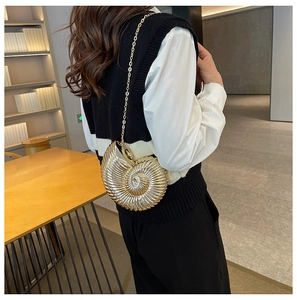 Close-up of golden shell-shaped acrylic evening bag with spiral texture and chain strap