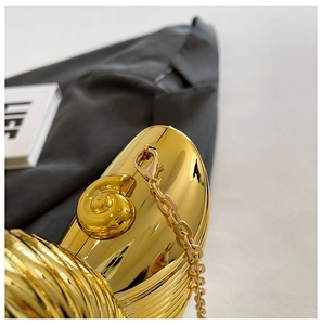 Detail of elegant gold shell evening clutch with metallic texture and sleek chain strap