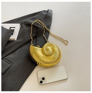 Macro detail of the golden nautilus shell clutch bag with a metallic chain strap