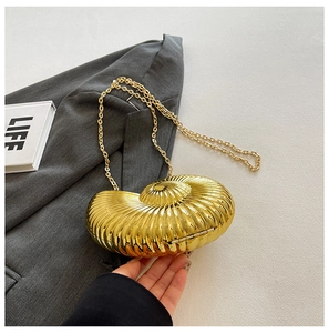 Detail of a golden seashell evening bag with metallic finish and delicate chain strap