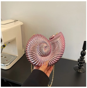Macro shot of metallic pink snail-shaped acrylic clutch bag with golden chain strap