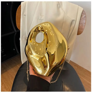 Detail of a gold metallic irregular evening bag with sculptural design and chain strap