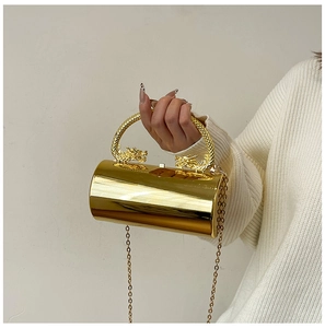 Détail d'un sac de soirée cylindrique doré avec des ornements de dragon en métal ciselé