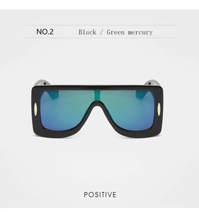 Vue de face des lunettes de soleil punk noires avec verres miroirs vert-bleu et décor doré