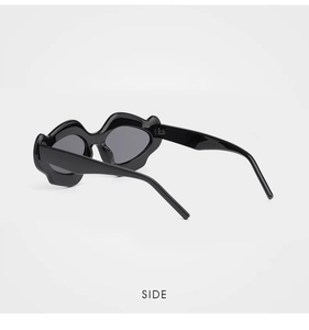 Vue latérale de lunettes de soleil tendance en forme de lèvres noires brillantes et verres gris