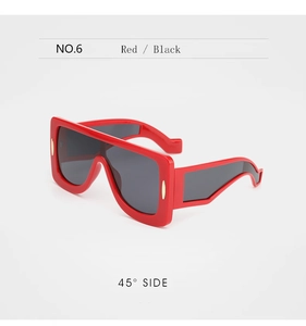 Détail de lunettes de soleil punk rouges avec garniture dorée et verres noirs à 45 degrés