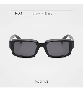 Vue de face de lunettes de soleil carrées noires avec verres foncés et détails en métal