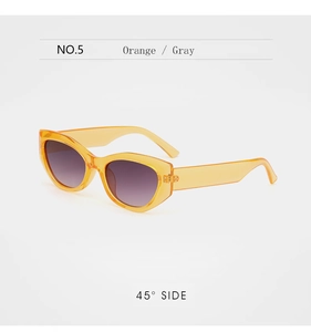 Close-up of cat-eye sunglasses with transparent orange frames and gradient gray lenses