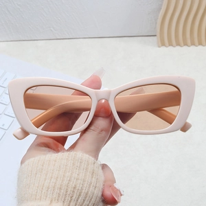 Retro beige cat eye sunglasses with light brown lenses shown in a hand-held lifestyle shot