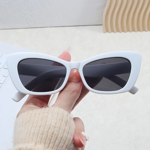 Close-up of white cat-eye sunglasses with dark lenses held to show size and texture