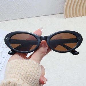 Detail shot of black oval sunglasses featuring silver triple-dot rivets and brown lenses
