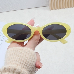 Chic oval sunglasses with yellow frames and silver rivets in a stylish hand-held pose