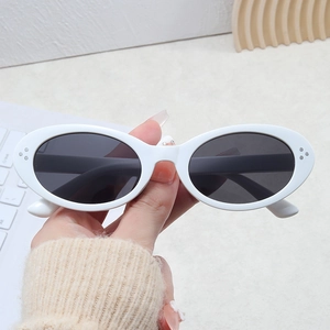Detail shot of oval white sunglasses with three-point silver metal rivets and grey lenses