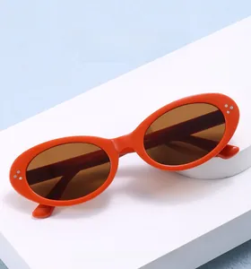 Chic orange oval sunglasses with silver dot rivets shown on geometric podiums