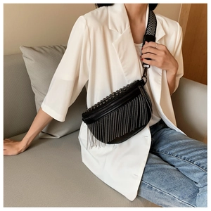 Detail of black leather crossbody bag with silver fringe and studded punk style details