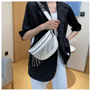 Close-up of white leather chest bag with silver studs, metal fringe and woven strap