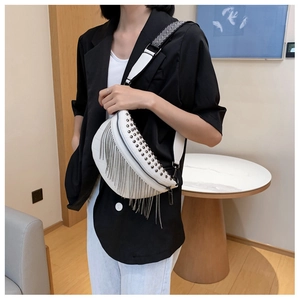 Close-up of white crossbody chest bag with metal rivets and long fringe tassels