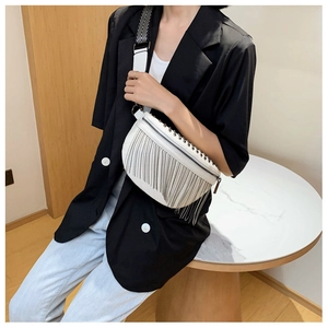 Close-up of white crossbody chest bag with silver metal fringes and studded details