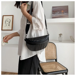 Detail of black crescent crossbody bag with silver studs and long metal tassels