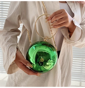 Dettaglio borsa da sera sferica verde smeraldo con manico ad anello dorato e catena