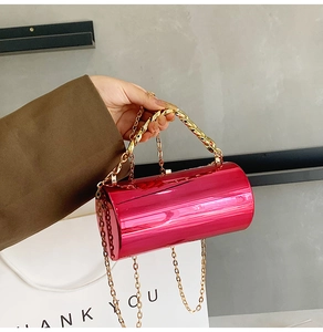 Detail of fuchsia cylindrical evening bag with gold chain handle and mirror finish