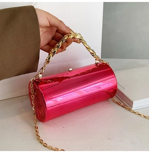 Detail showing fuchsia acrylic cylinder bag with shiny mirror finish and gold chain handle