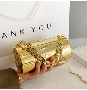 Detail of a cylinder evening bag with gold mirror finish and dual chain handles