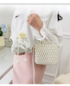 Détail du sac seau en perles avec doublure en satin crème et bandoulière chaîne dorée