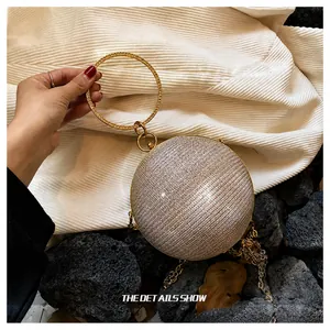 Detail of spherical evening bag with rhinestones, metal ring handle, and chain strap