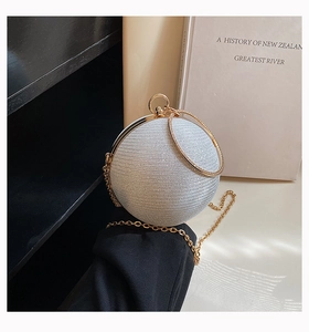 Detailed view of spherical rhinestone evening bag with gold circular handle and chain