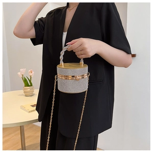 Detail van sprankelende strass cilinder tas met gedraaid goud handvat en ketting