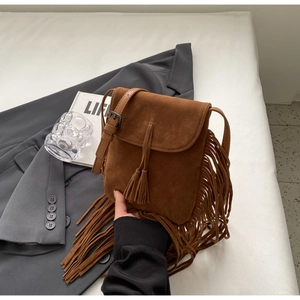 Détail d'un sac bandoulière bohème en daim marron avec de longues franges et glands