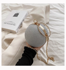 Detailed shot of silver spherical clutch with rhinestone ring handle and golden metal chain